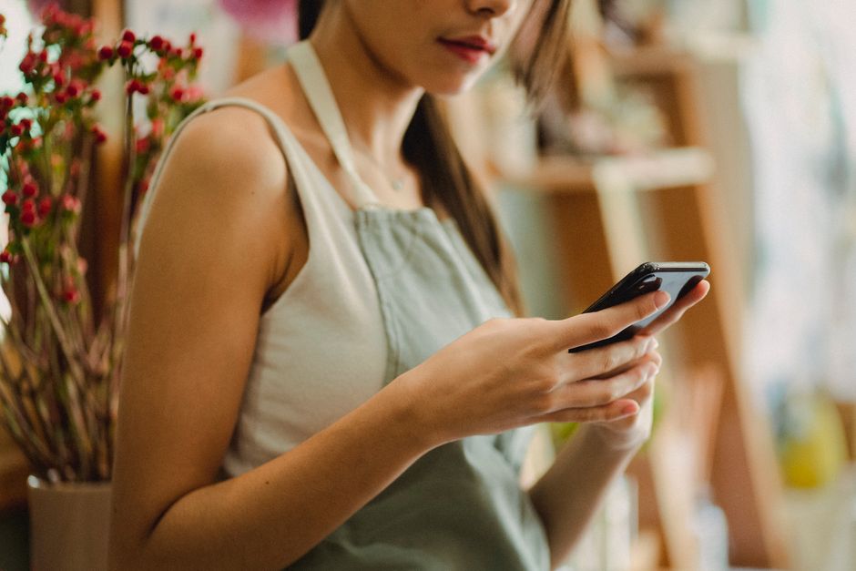 Dependienta de una floristería consulta el móvil en su tienda: reseñas de Google de un negocio local