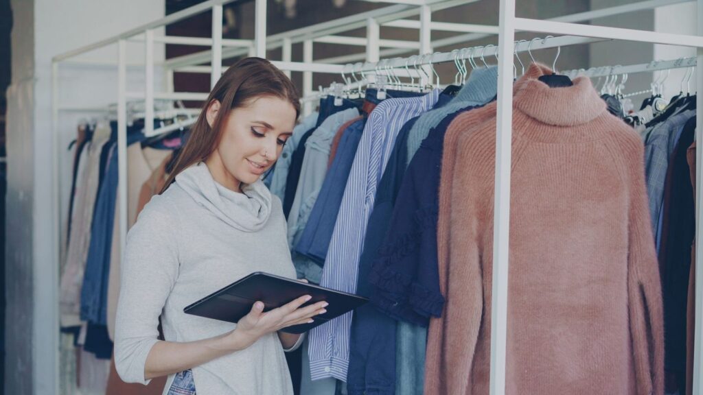 Cómo gestionar varias fichas de Google Business Profile (cadenas y franquicias) 3 Empleada de una tienda de ropa revisando datos en una tableta: gestionar la ficha de cada sede