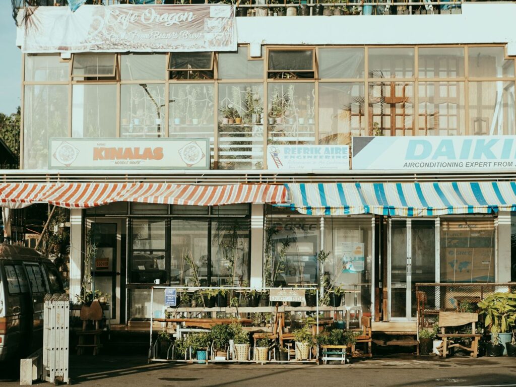 Cómo gestionar varias fichas de Google Business Profile (cadenas y franquicias) 4 Calle con varios comercios y toldos de colores: cada sede de una cadena compite en su propia zona