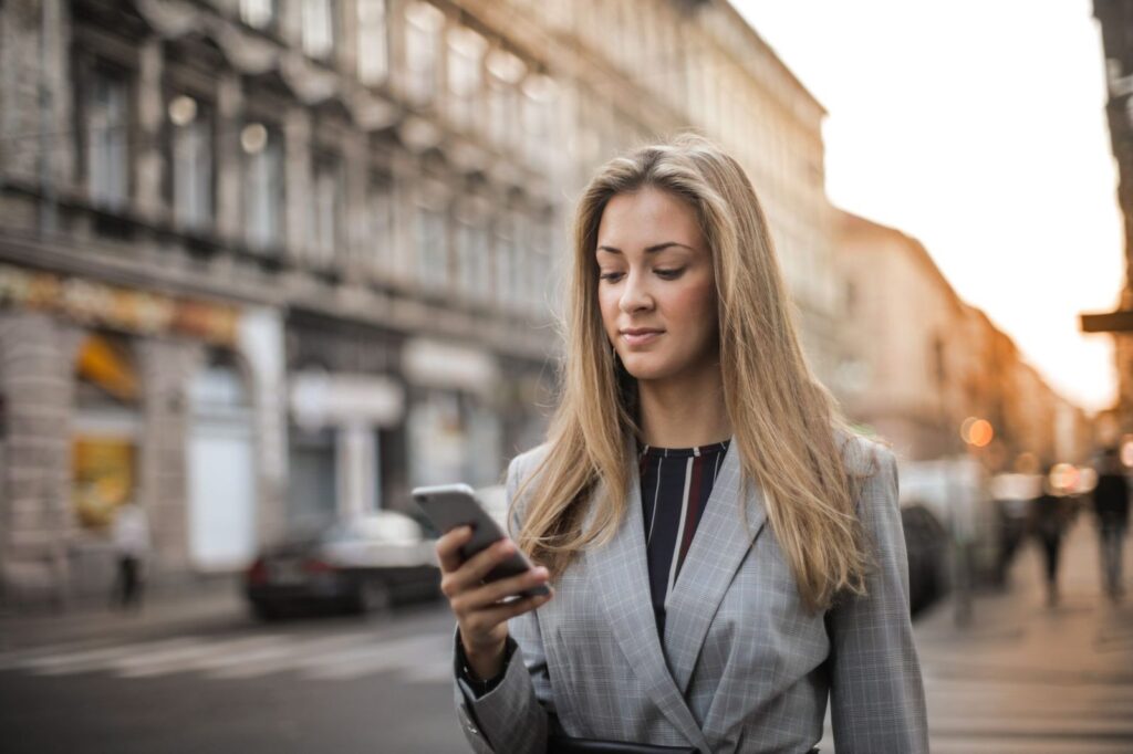 Modo IA de Google: qué es y cómo elige los negocios que recomienda 4 Mujer caminando por la calle mientras consulta el móvil: búsquedas locales con el modo IA