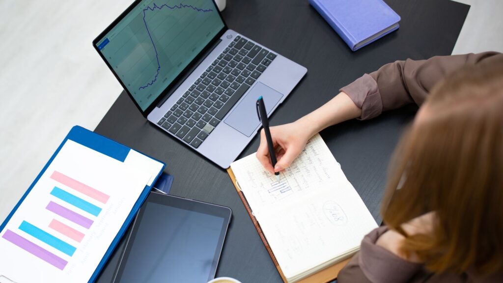¿Te recomienda ChatGPT? Cómo medirlo, con 71 respuestas de IA analizadas 3 Persona anotando resultados junto a un portátil con gráficos: medir la visibilidad en IA cada mes