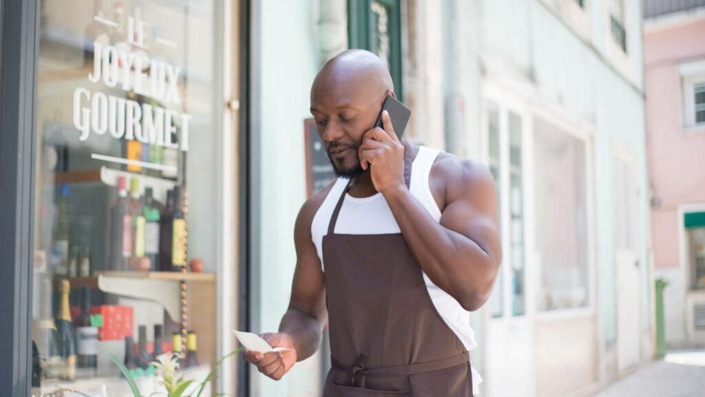 ¿Te recomienda ChatGPT? Cómo medirlo, con 71 respuestas de IA analizadas 4 Dueño de una tienda hablando por teléfono a la puerta del local: negocios locales y recomendaciones de la IA