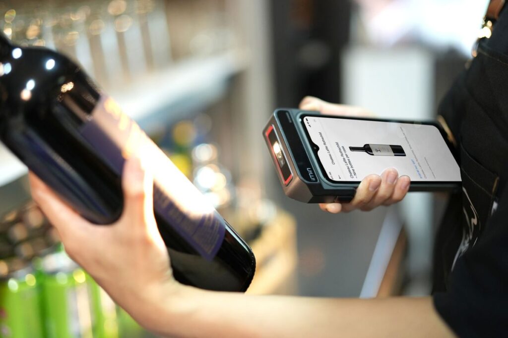 Inventario local en Google: cómo enseñar el stock de tu tienda física en Google y en Maps 4 Empleada escaneando una botella con un lector en una tienda: inventario local en Google