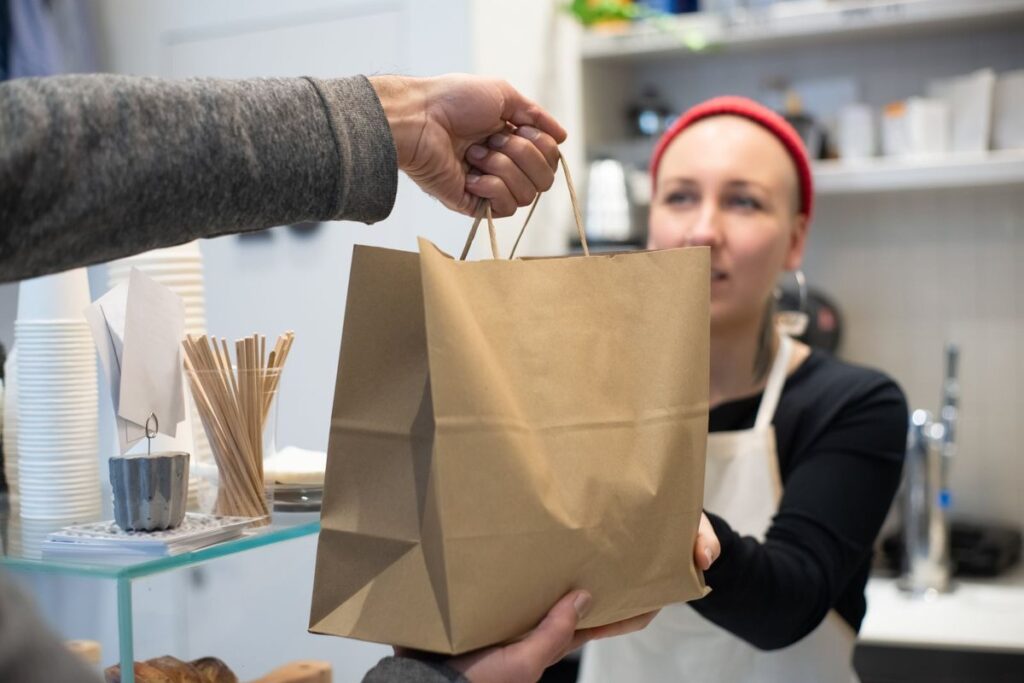 Inventario local en Google: cómo enseñar el stock de tu tienda física en Google y en Maps 4 Dependienta entregando un pedido en el mostrador: recogida en tienda con inventario local de Google