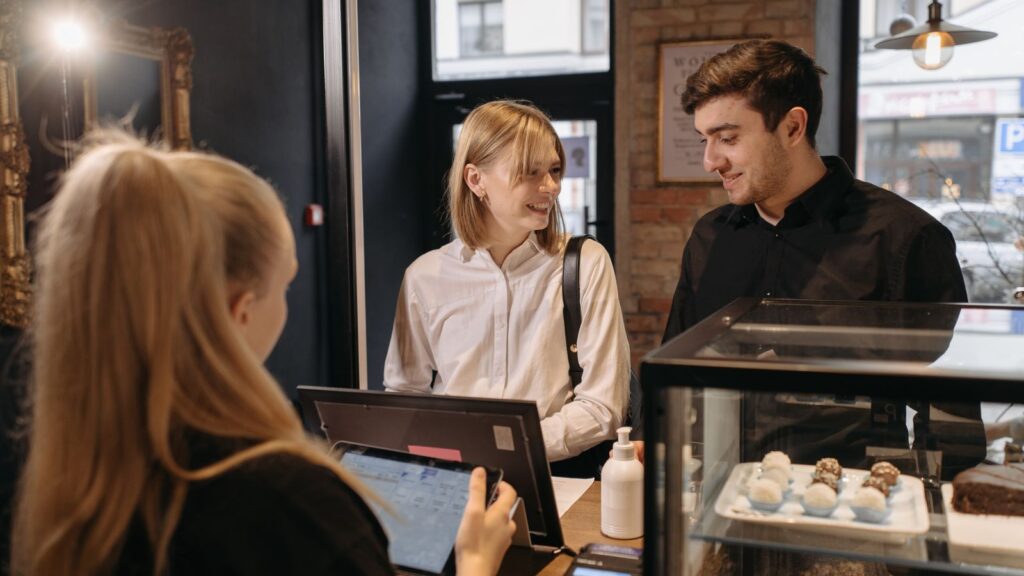 SEO local para franquicias: quién controla las fichas, la web y las reseñas 5 Clientes pidiendo en el mostrador de una cafetería: SEO local para franquicias con varios locales