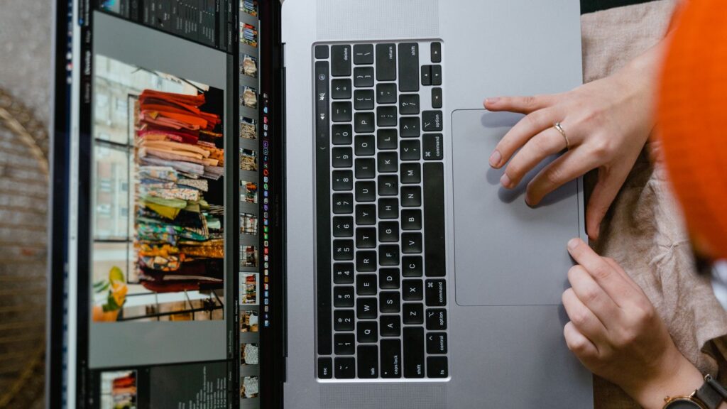 SEO en PrestaShop: guía práctica para tiendas online con tienda física 3 Persona revisando fotos de productos en un portátil para las fichas de una tienda PrestaShop